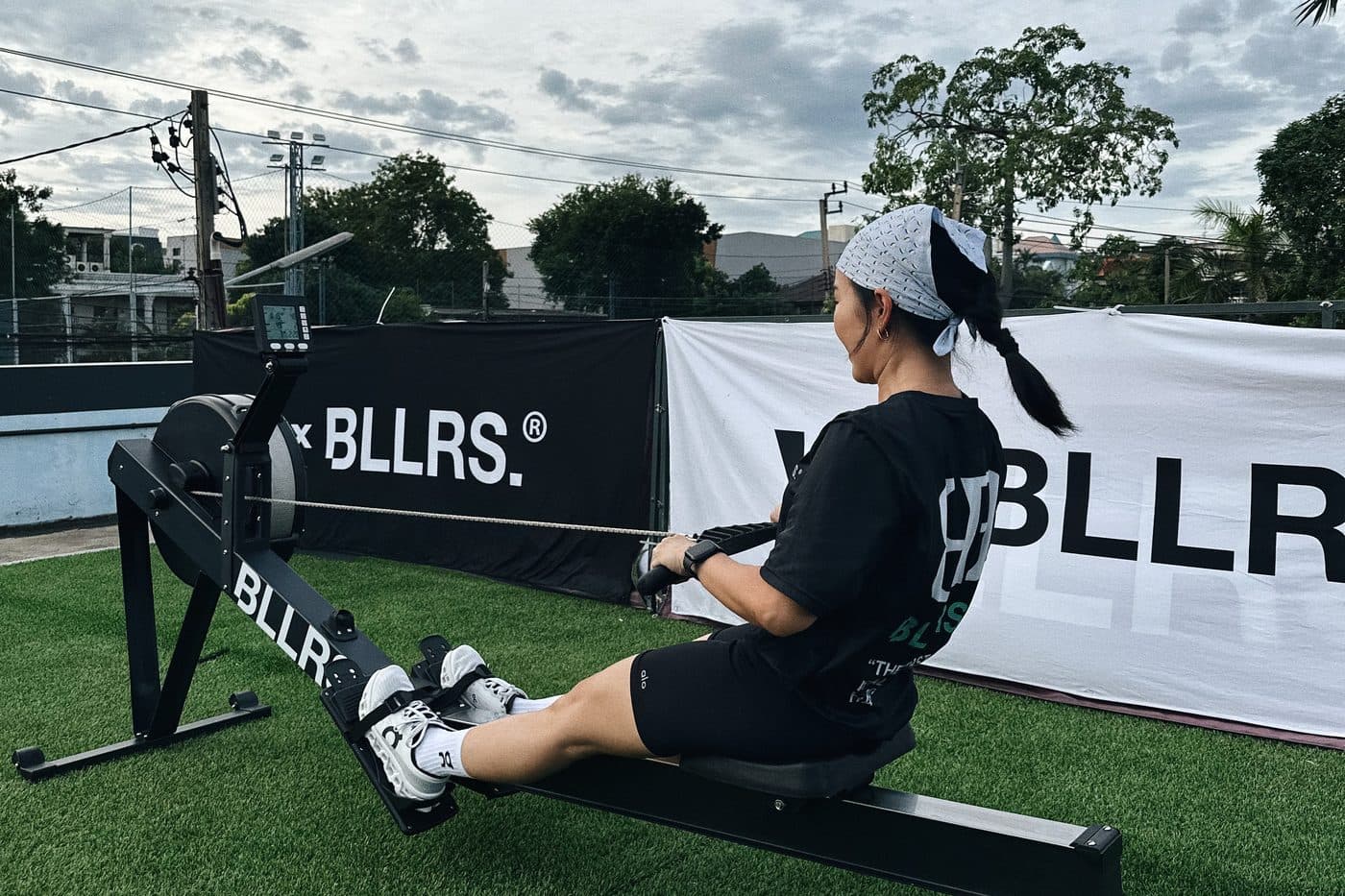 A participant on the rowing machine on the BALLERS Bangkok pitch at dusk
